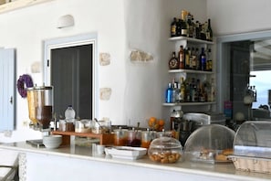 A breakfast bar with various food items, condiments, and a coffee machine. - Ambelas Mare (Paros)