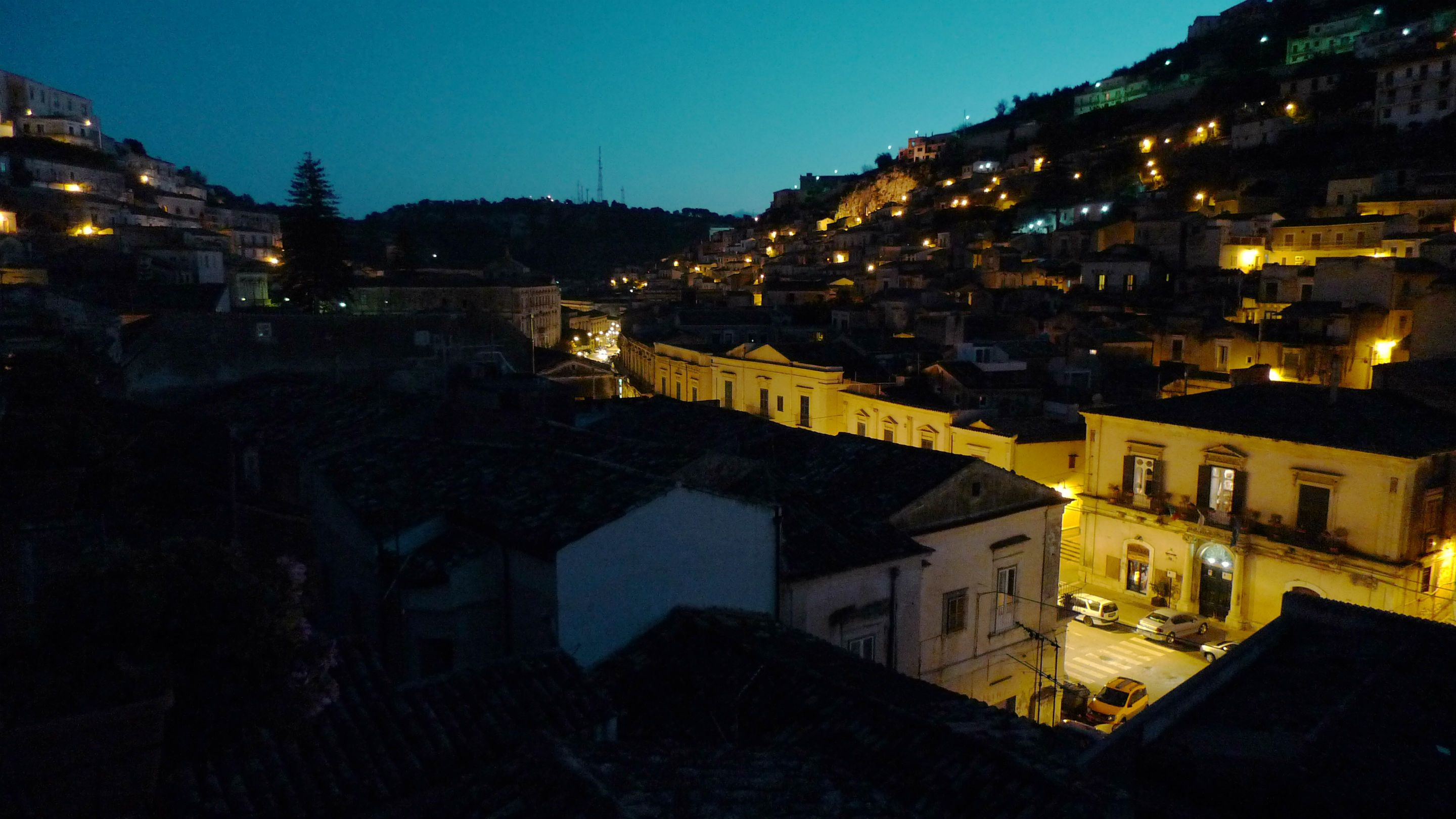A nighttime view of a historic town with illuminated buildings and a prominent church.