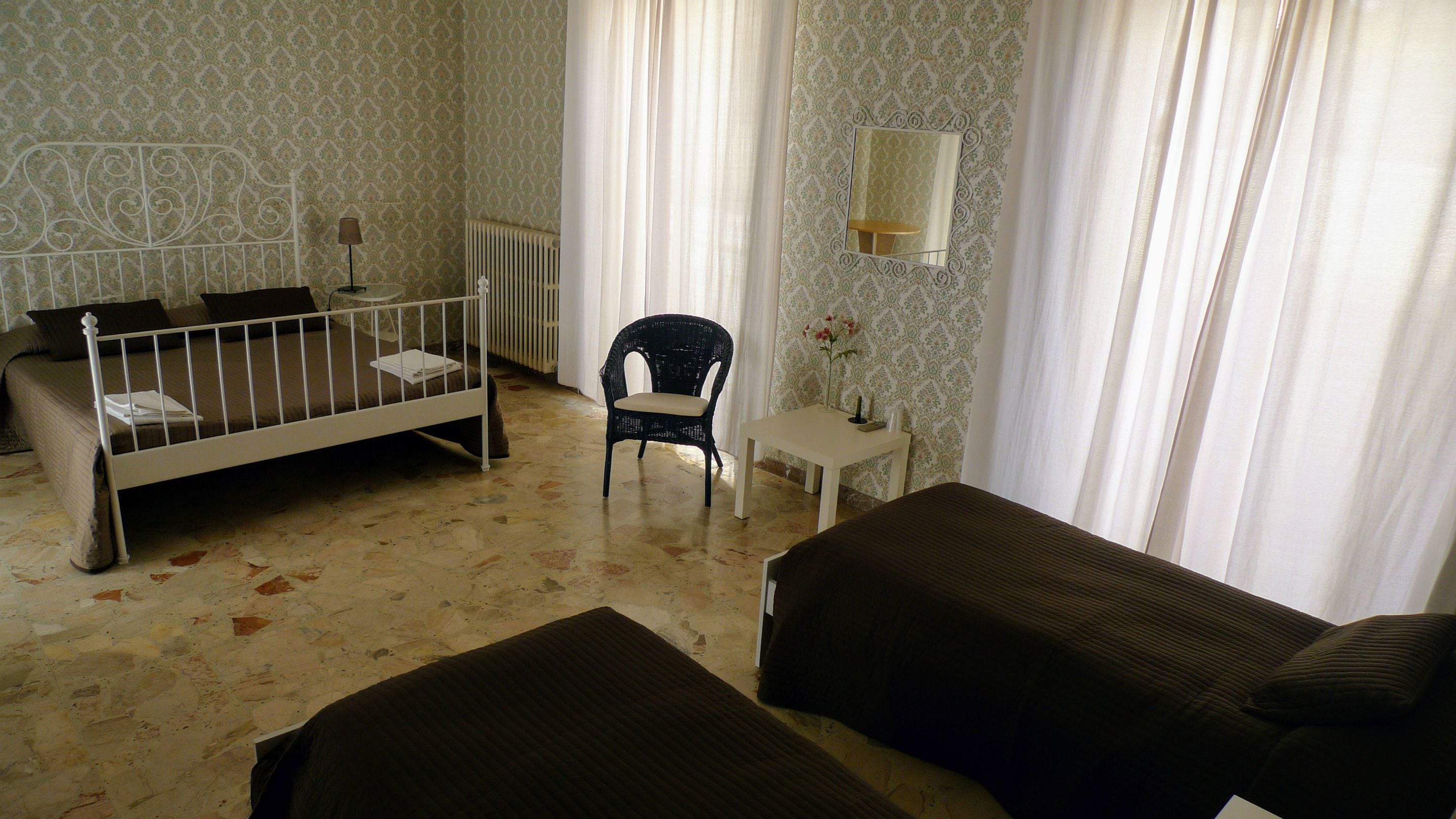 Una stanza con un letto, un tavolino, una sedia e uno specchio a parete.