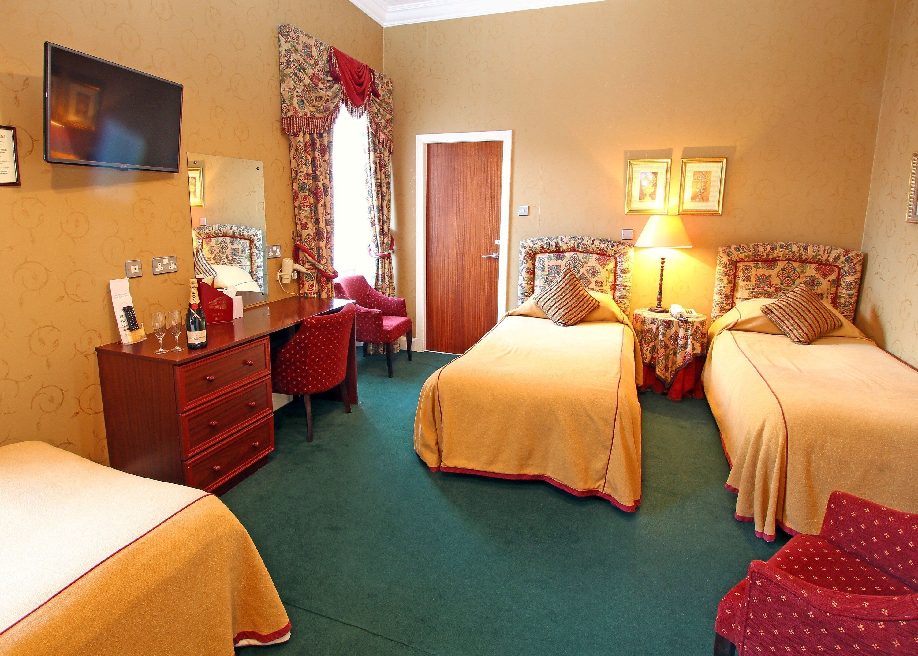 A hotel room with two beds, a desk with a chair, a TV, a mirror, and a door.