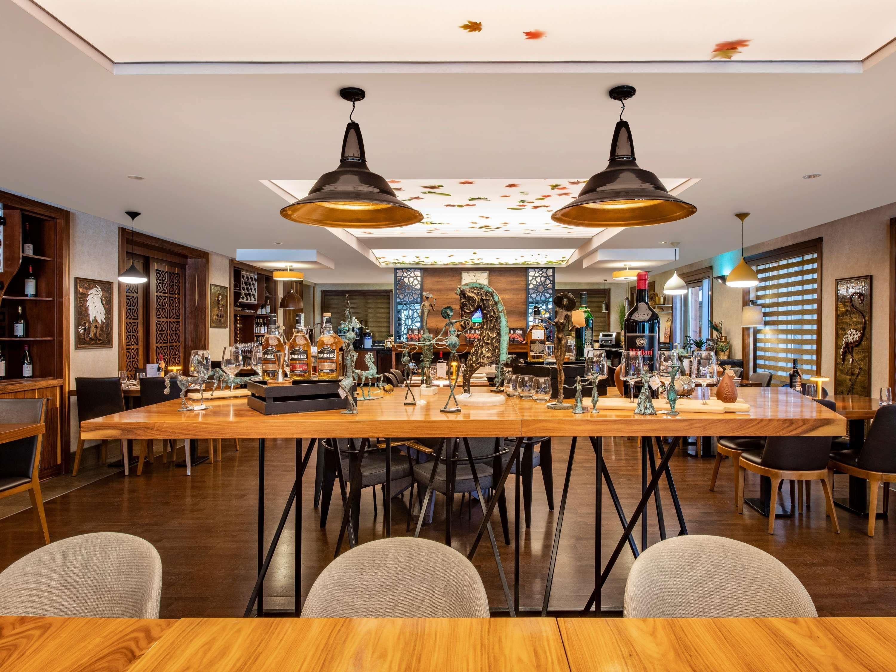 A spacious dining area with a long wooden table, black metal chairs, and two pendant lights.