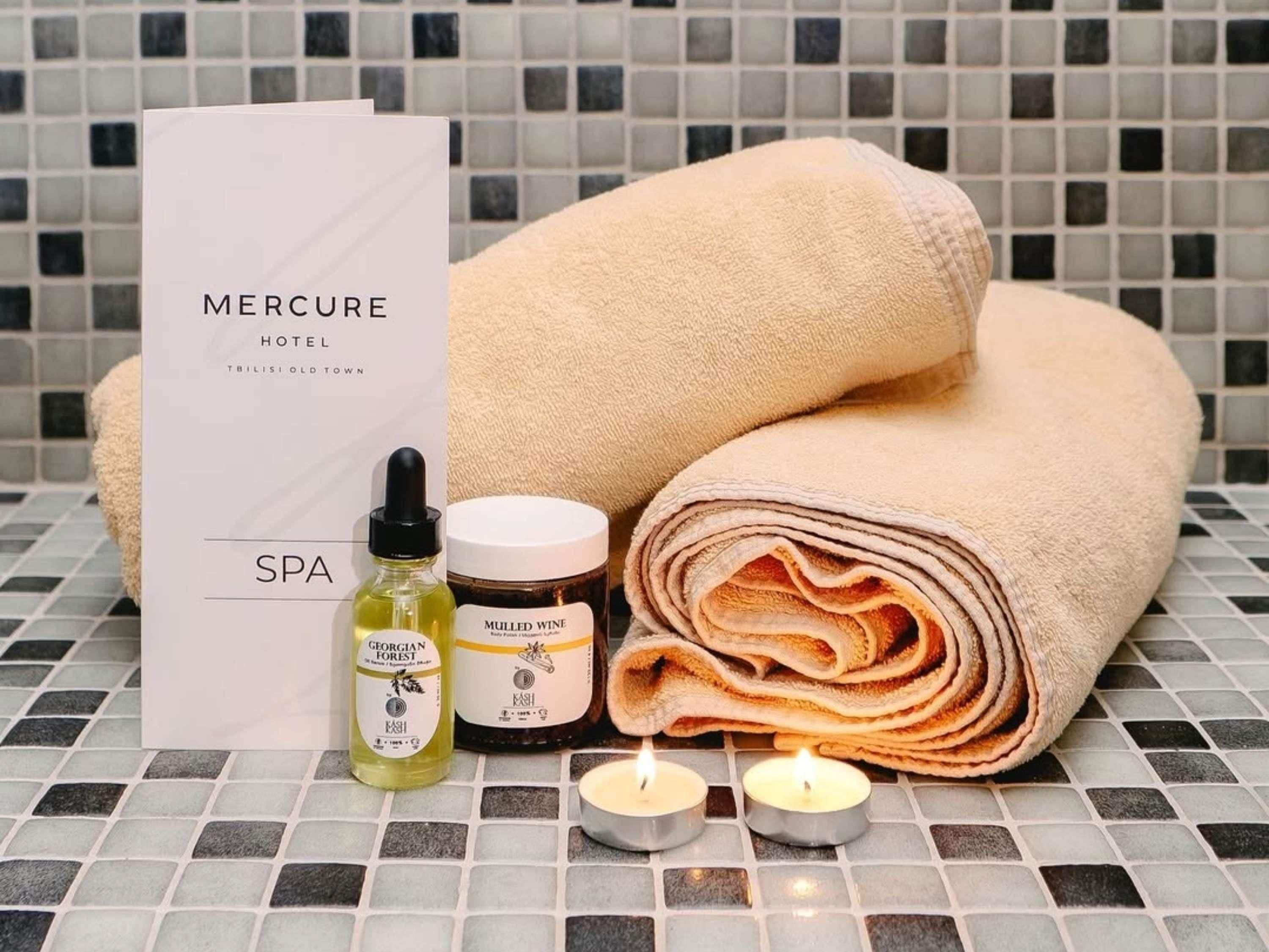 Een wellnessarrangement met handdoeken, kaarsen en huidverzorgingsproducten.
