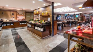 A modern hotel lobby with a buffet area, seating, and a bar.