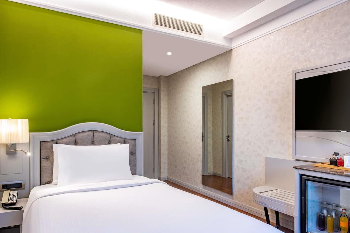 Une chambre d’hôtel avec un lit, une télévision, un minibar et une porte de salle de bain.