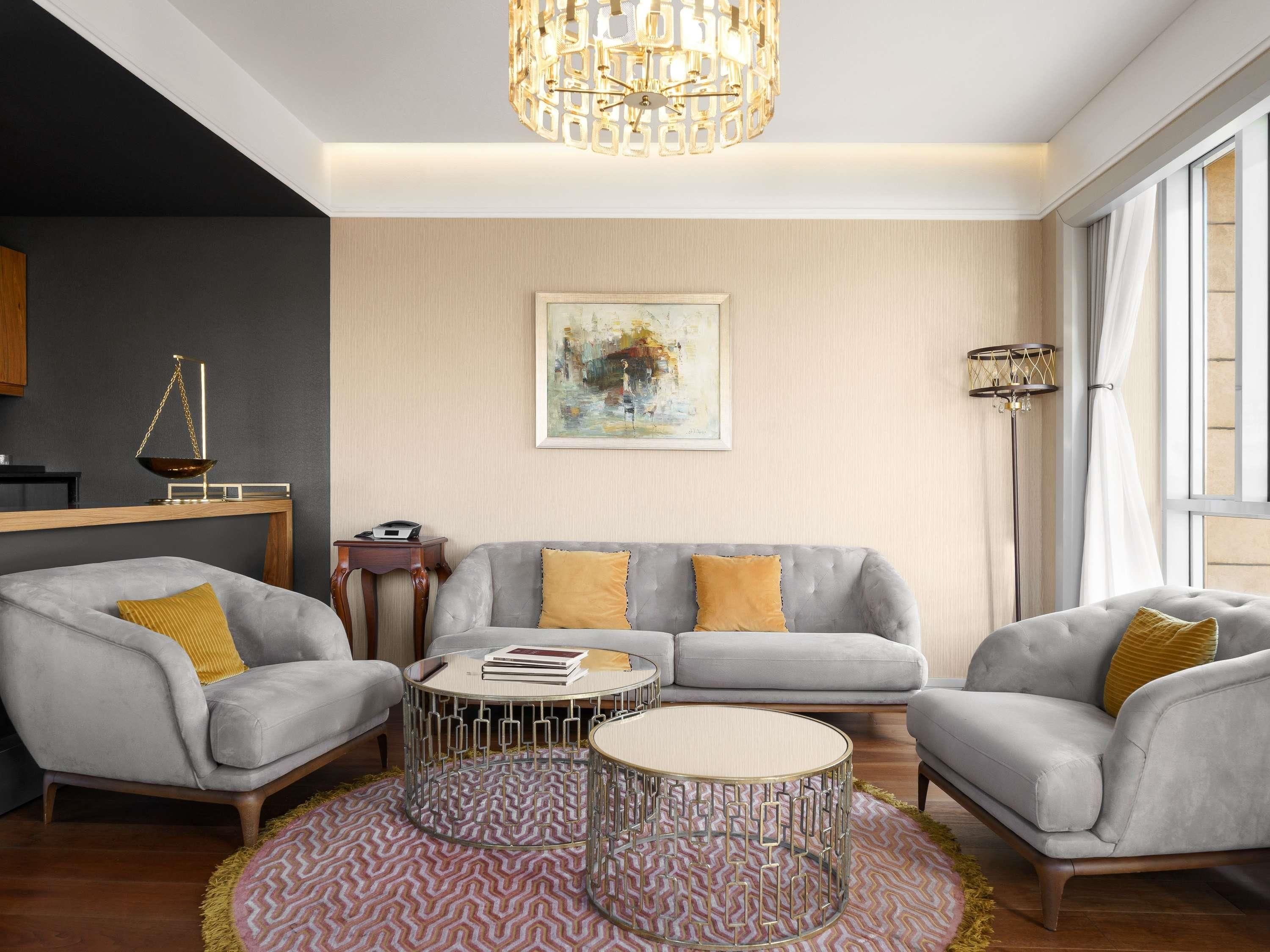 A modern living room with a grey sofa, two armchairs, a coffee table, and a decorative floor lamp.