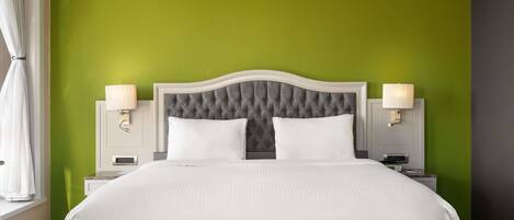 A neatly made bed with white linens, a tufted headboard, and two bedside lamps.