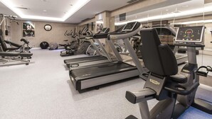 Un gimnasio con cintas de correr, máquinas elípticas y equipo de pesas.