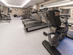 Un gimnasio con cintas de correr, máquinas elípticas y equipo de pesas.