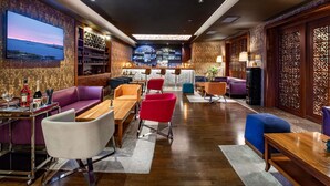 Un área de bar con asientos, una pantalla de televisión y una barra.