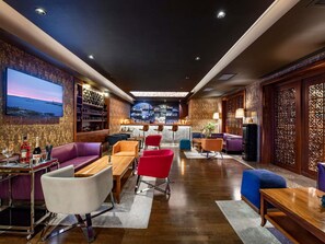 A bar area with seating, a TV screen, and a bar counter. - Mercure Tbilisi Old Town (Tbilisi)