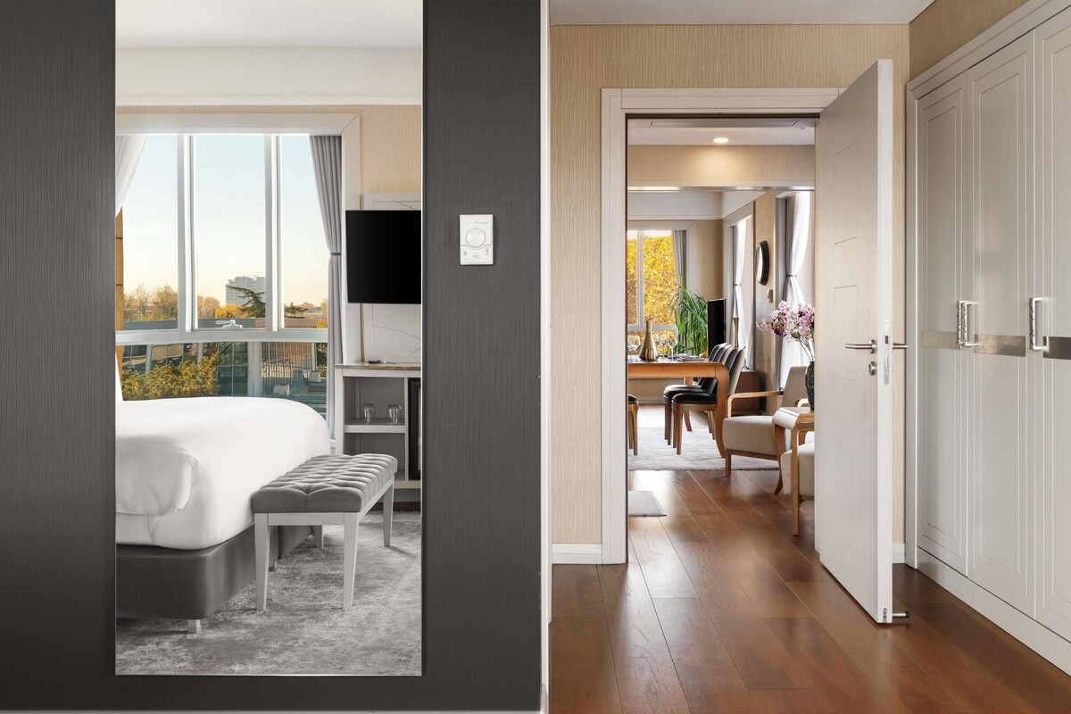 Una habitación de hotel con cama, escritorio, televisión y vista a la ciudad.