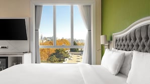 Una habitación de hotel con una cama grande, televisión y ventana con cortinas.