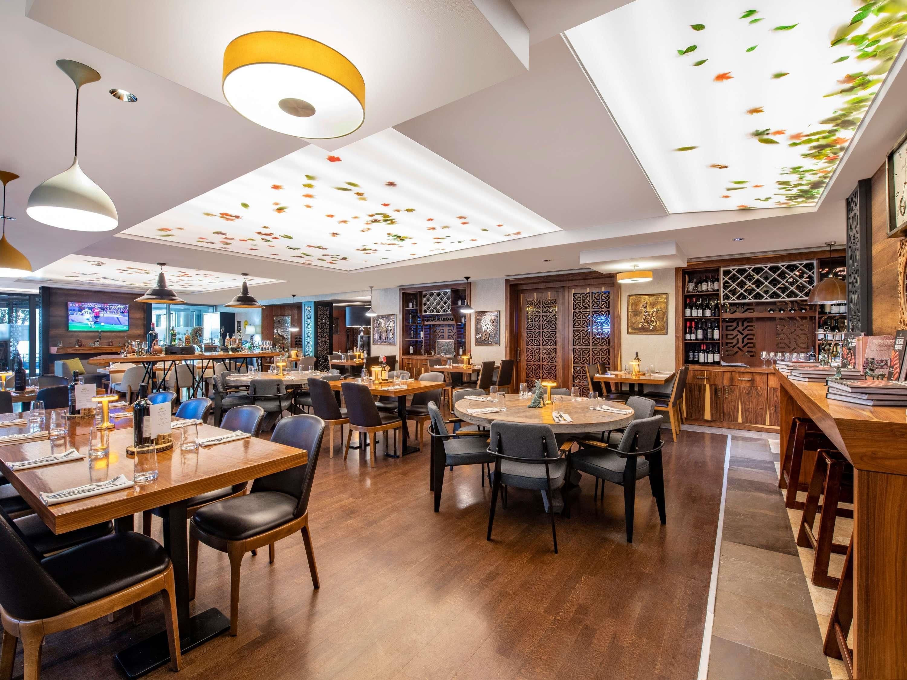 A restaurant with multiple dining areas, wooden tables, and chairs.