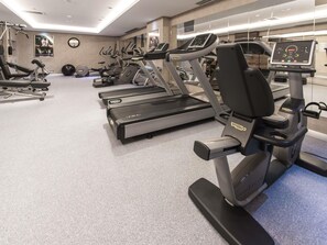 Un gimnasio con cintas de correr, máquinas elípticas y equipo de pesas.