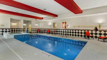 Ein Innenpool mit einer Wassertiefe von etwa 1,2 Metern, umgeben von Wänden mit rot-schwarzem Schachbrettmuster, ausgestattet mit roten und schwarzen Liegestühlen.