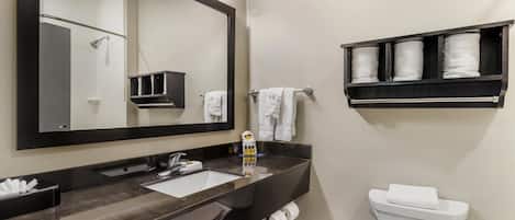 Une salle de bain moderne avec un grand miroir, un lavabo, des toilettes et une étagère avec des serviettes.