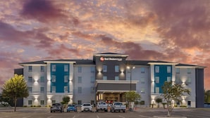 A Best Western PLUS hotel with a modern design, featuring multiple floors and a parking lot with several vehicles. - Best Western Plus Laredo Inn & Suites (Laredo)