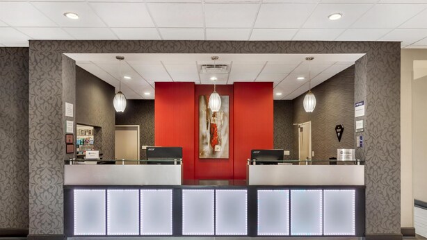 A reception area with a red accent wall, two reception desks, and a modern chandelier. - Best Western Plus Laredo Inn & Suites (Laredo)