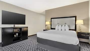 A hotel room with a large bed, a flat-screen TV, a minibar, and two bedside lamps.