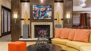 A hotel lobby with a fireplace, seating area, and artwork on the wall.