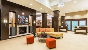 A spacious lobby with a fireplace, a large sofa, and a reception desk.
