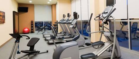 Une salle de sport équipée de tapis de course, de vélos elliptiques et d’un vélo d’appartement.