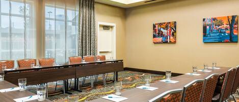 A conference room with a long table, chairs, and a carpeted floor.