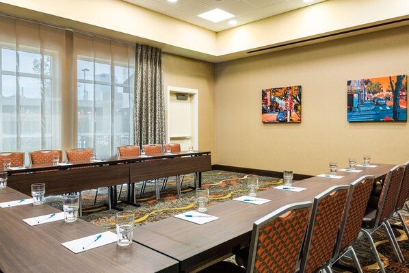 A conference room with a long table, chairs, and a carpeted floor.