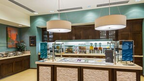 A breakfast bar with a glass display case, wooden cabinets, and pendant lighting.