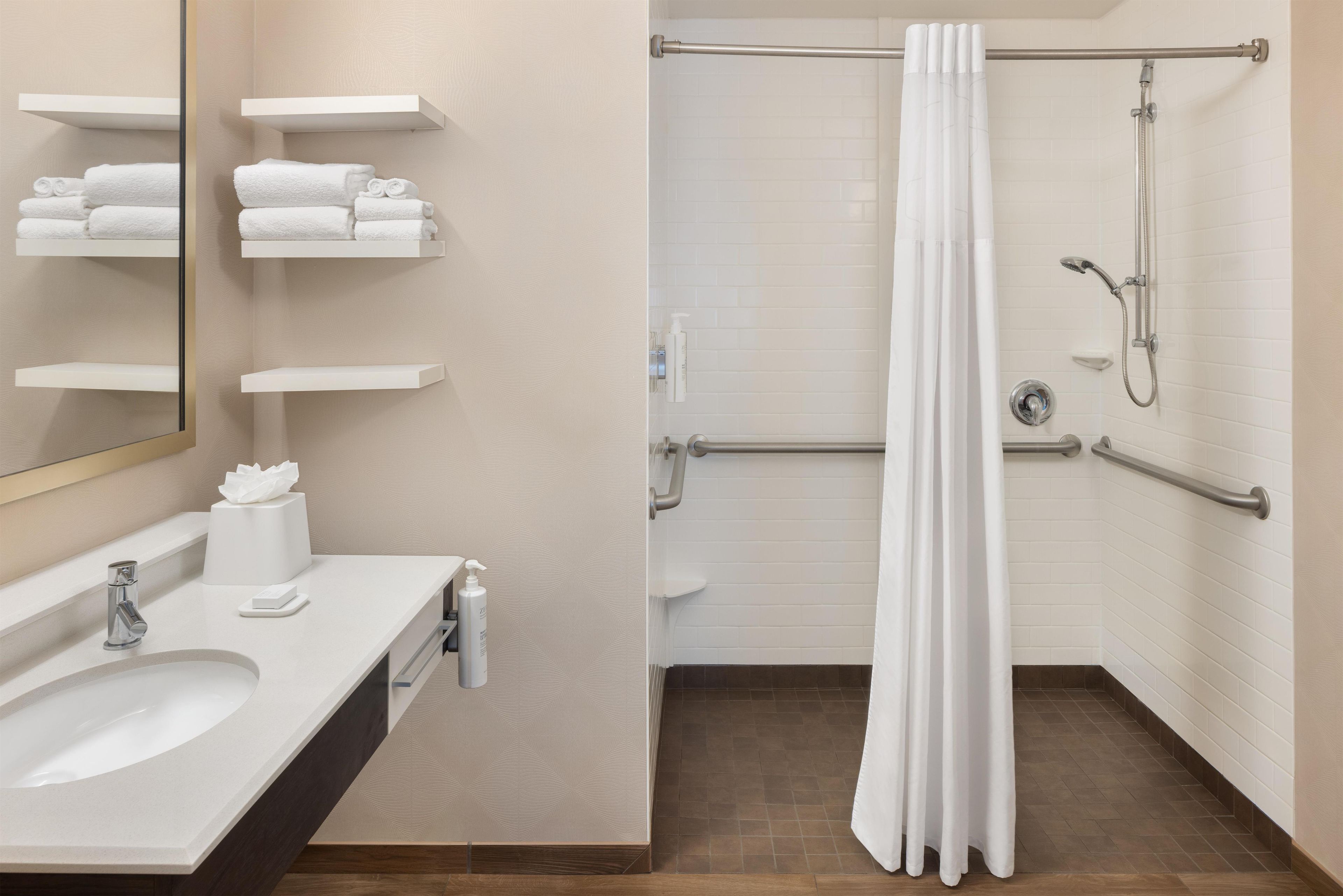 A modern bathroom with a sink, mirror, towel rack, and shower area.