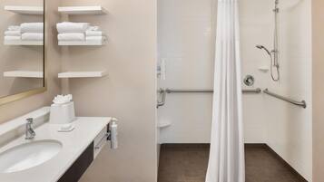 A modern bathroom with a sink, mirror, towel rack, and shower area.