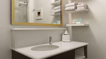 Un baño con un lavamanos blanco, un espejo con marco dorado y estantes con toallas dobladas cuidadosamente.