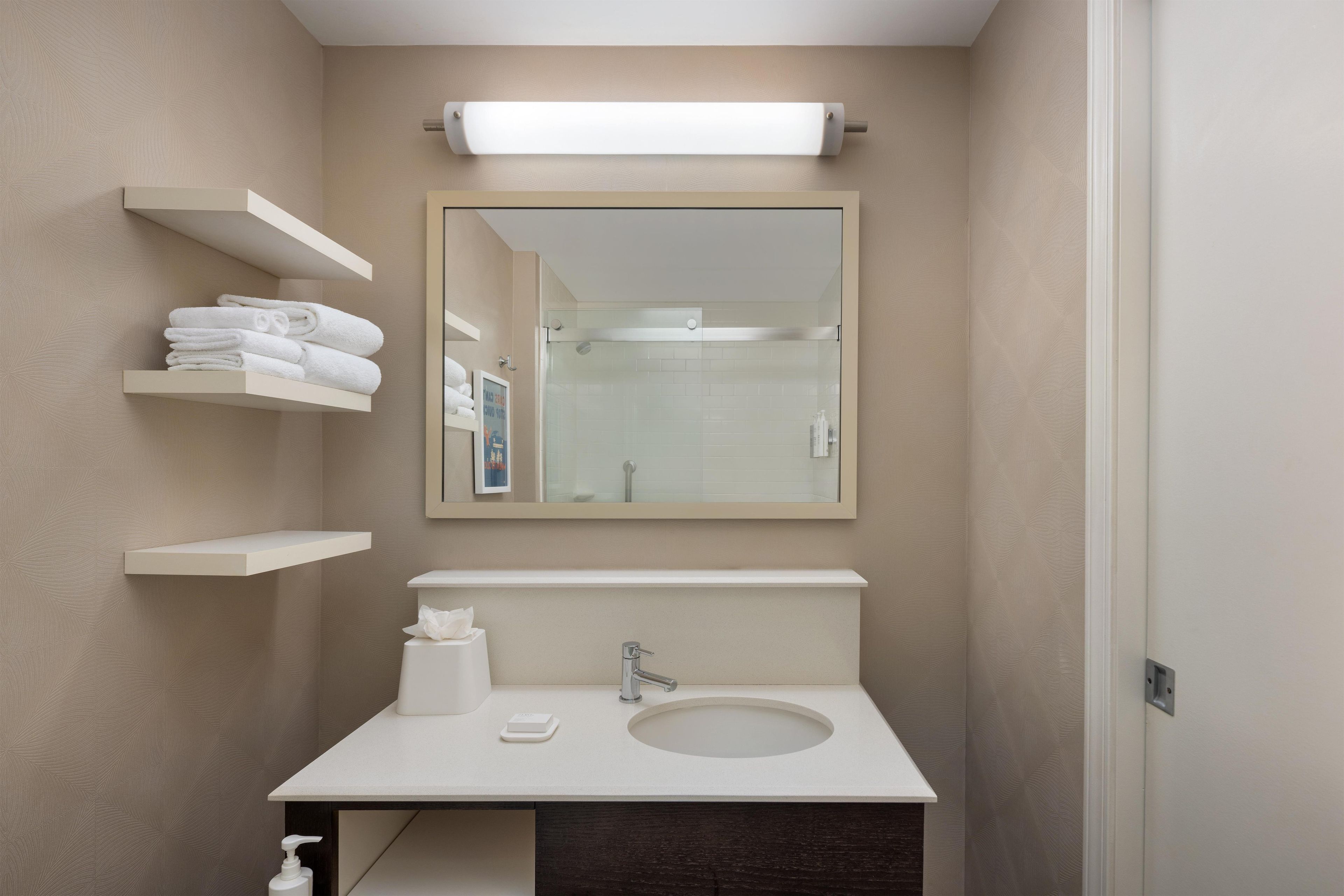 A modern bathroom with a white sink, a mirror, and a towel rack.