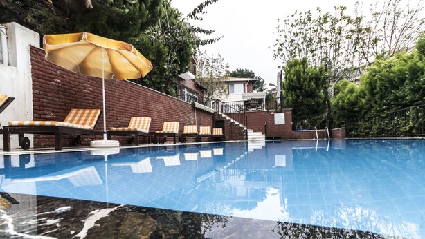 A swimming pool with lounge chairs and an umbrella. - Büyükada Apart Hotel - Karadağ Apart (Adalar)