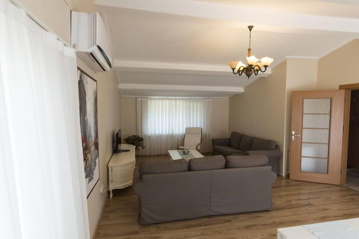 A living room with a sectional sofa, a white coffee table, a lamp, and a door leading to another room.