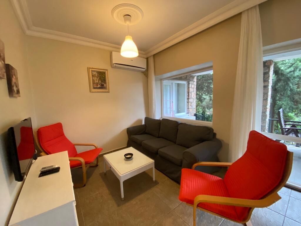 A living room with a sofa, two red chairs, a white coffee table, and a television.