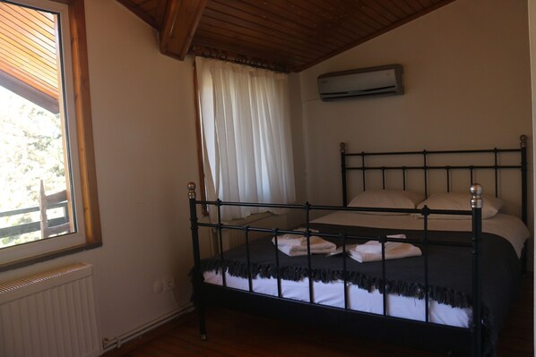 Un dormitorio con cama, ventana con persianas, aire acondicionado y radiador.