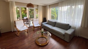 A living room with a sofa, two chairs, a glass coffee table, and a ceiling fan. - Büyükada Apart Hotel - Karadağ Apart (Adalar)