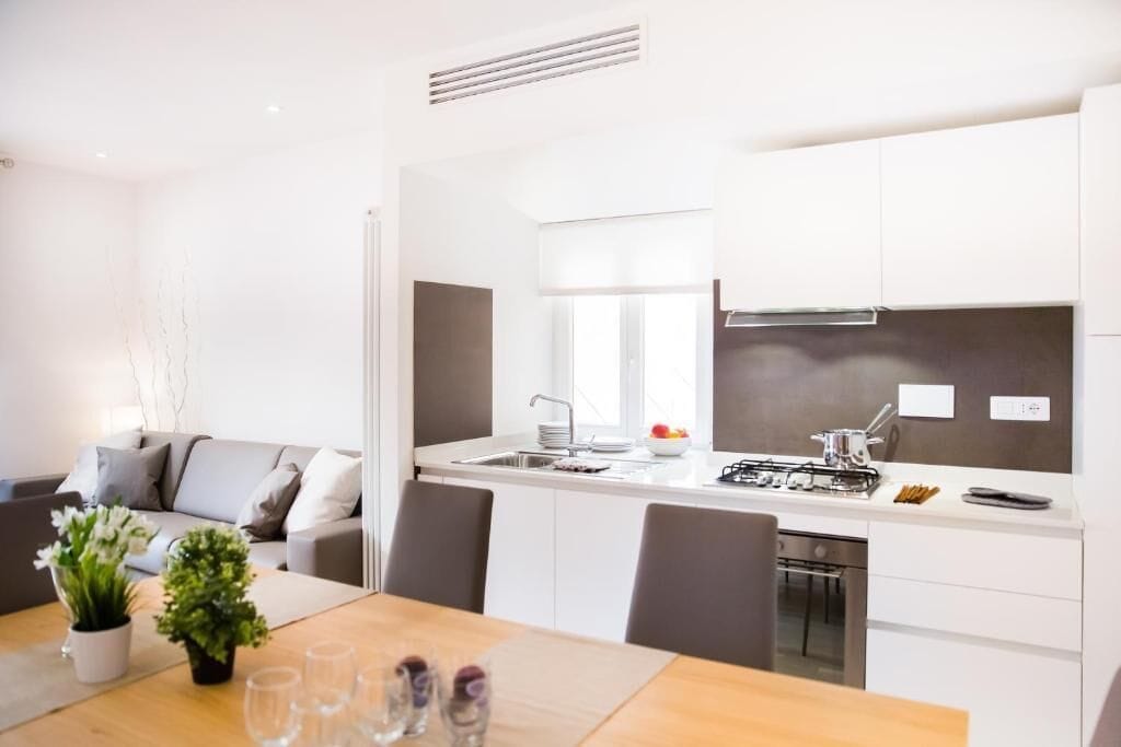 A modern kitchen with white cabinets, a built-in oven, and a window above the sink.