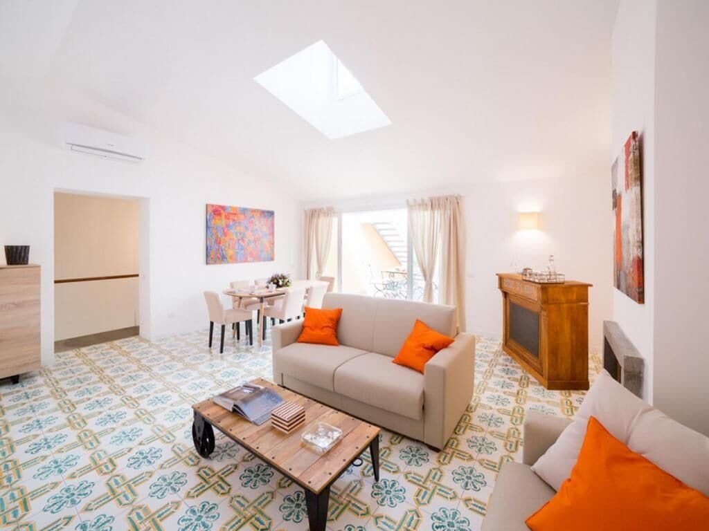 Uma sala de estar com sofá, mesa de centro e uma área de jantar com cadeiras.