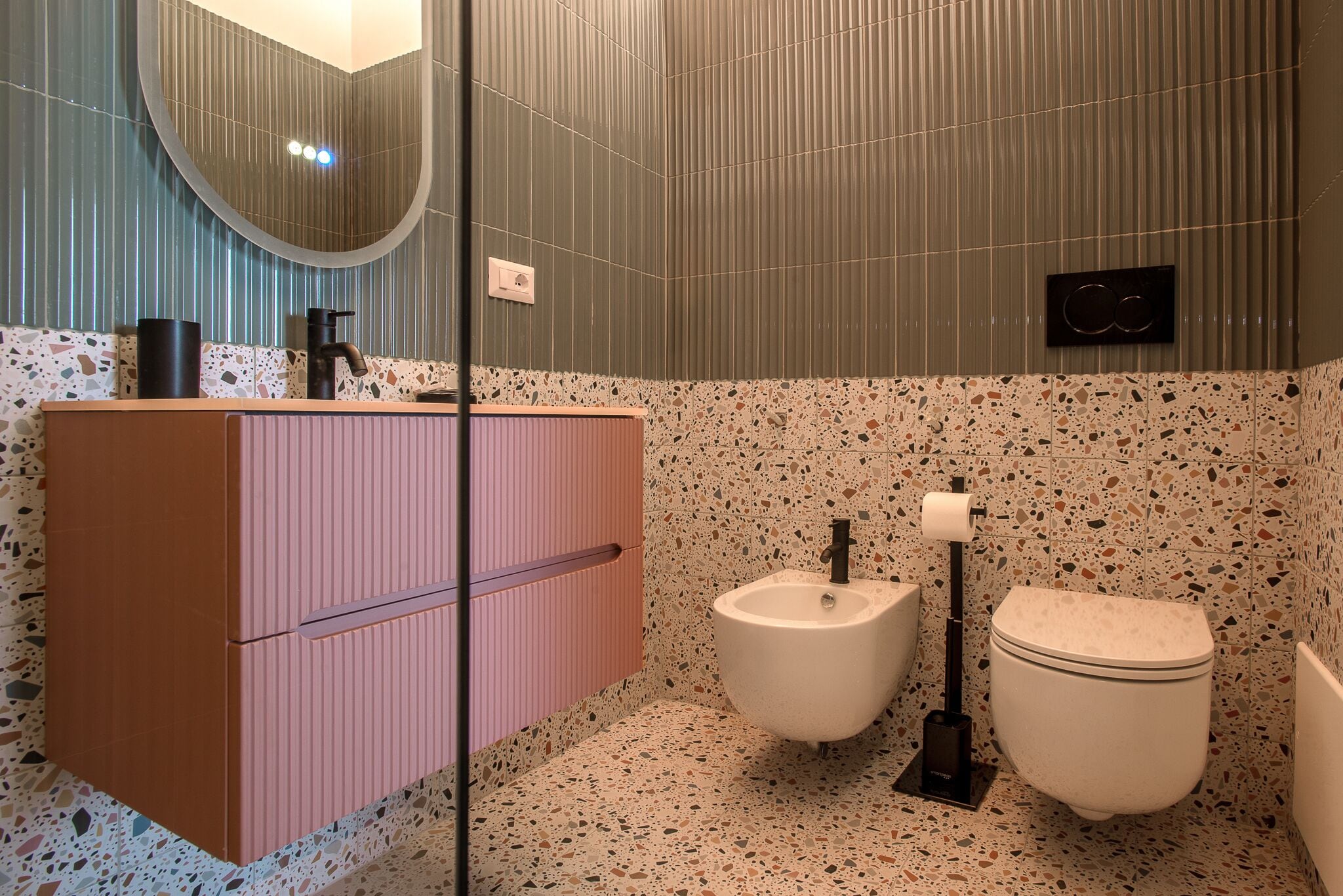 Un baño con tocador rosa, un bidé y un inodoro.