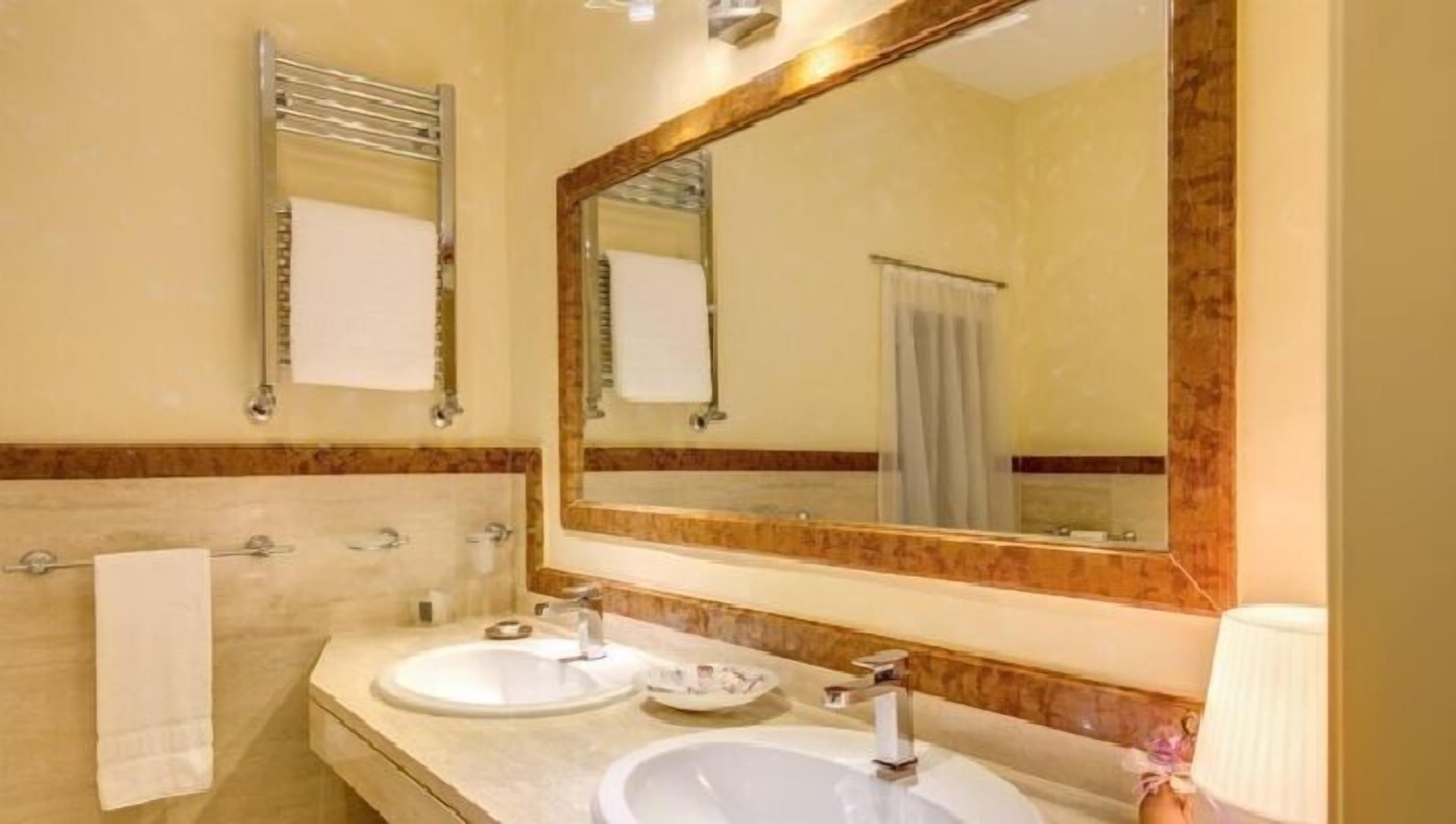 Une salle de bain avec deux lavabos, un grand miroir et un porte-serviettes.