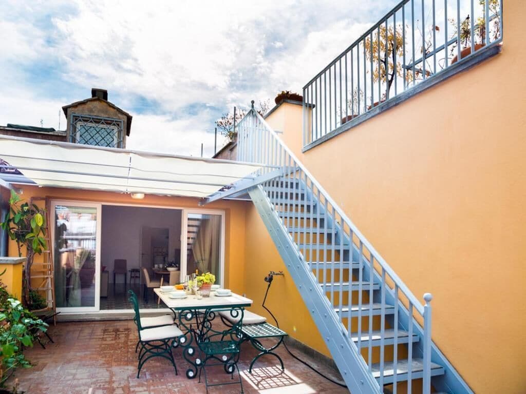 A patio with a table and chairs, a blue staircase, and a yellow wall.