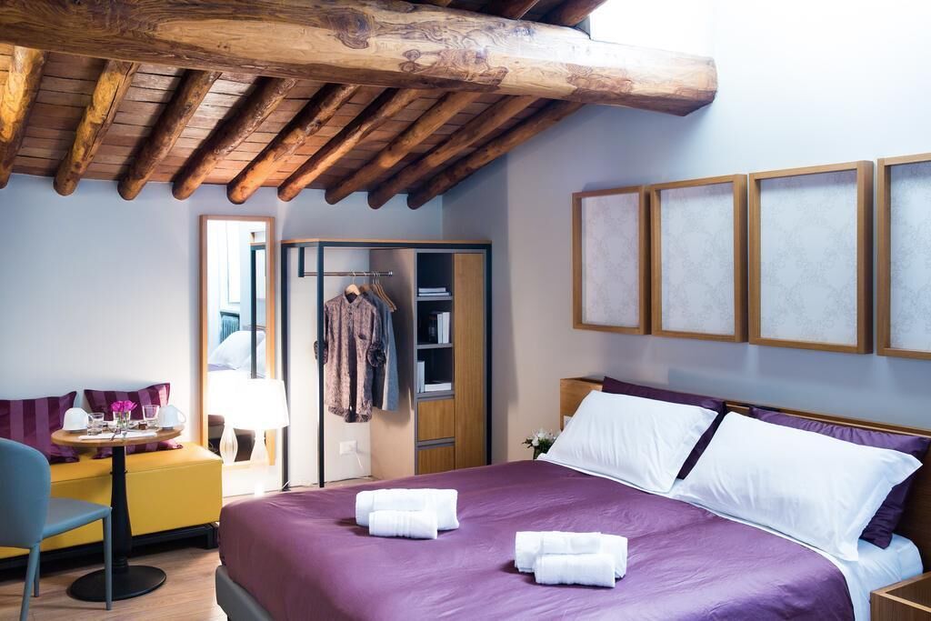 A hotel room with a bed, a desk, a chair, a wardrobe, and a mirror.