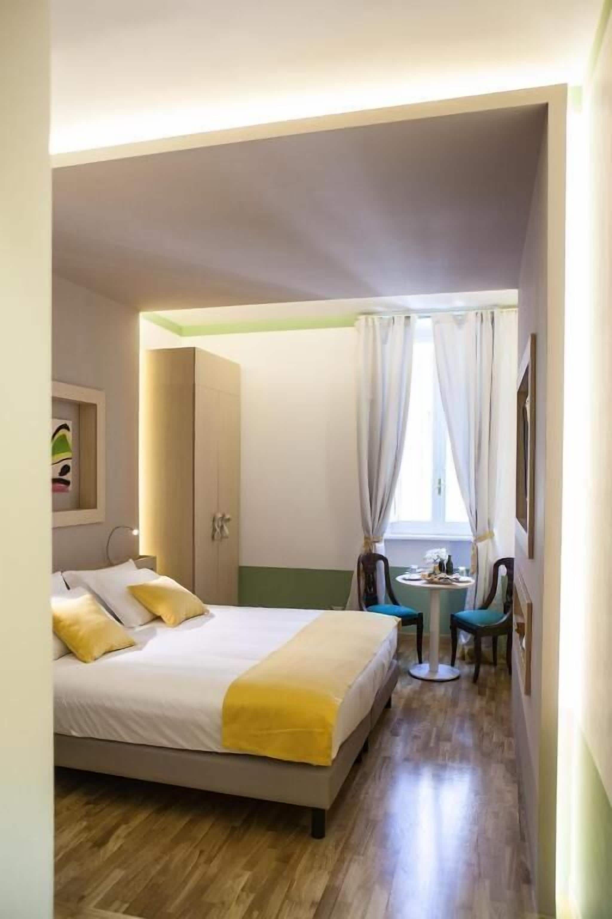 A compact hotel room with a bed, a small round table, and a chair.