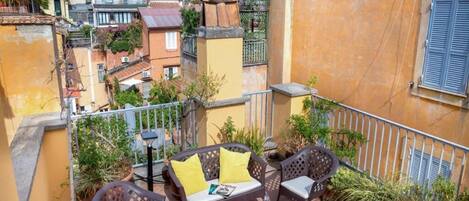 A balcony with outdoor furniture, including a sofa and chairs, surrounded by potted plants.