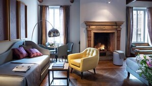 Een gezellige woonkamer met een open haard, een bank, een gele fauteuil en een eethoek.