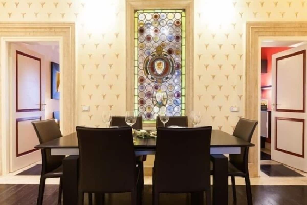 A dining area with a table set for four, flanked by two doors and a decorative stained glass window.