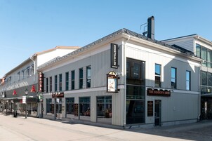 Un hotel con fachada clásica, grandes ventanales y un llamativo letrero que dice 'The Bishop's Arms'.