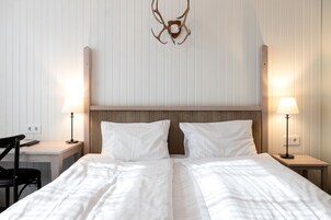 Una habitación de hotel con una cama grande, dos mesitas de noche, un escritorio y una silla.